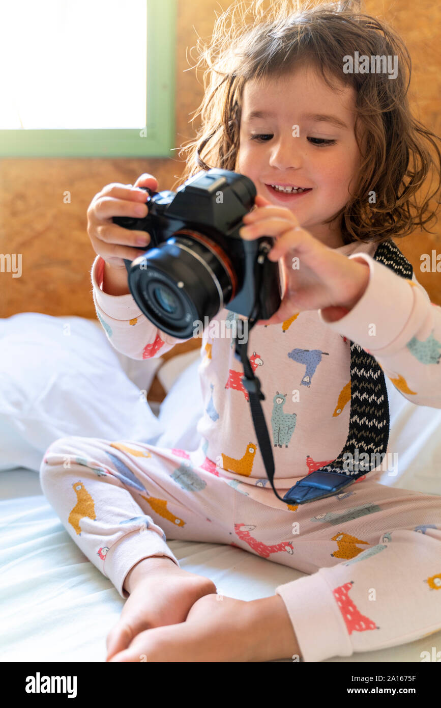 Süße kleine Mädchen im Schlafanzug im Bett mit einer Kamera Stockfoto