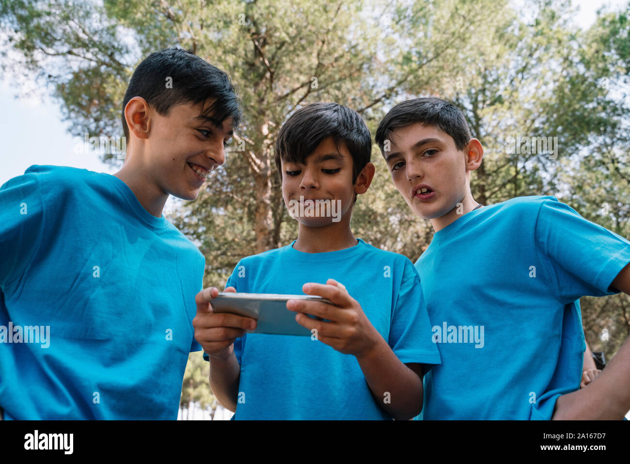 Drei Männer in blauen T-Shirts mit Smartphone Stockfoto