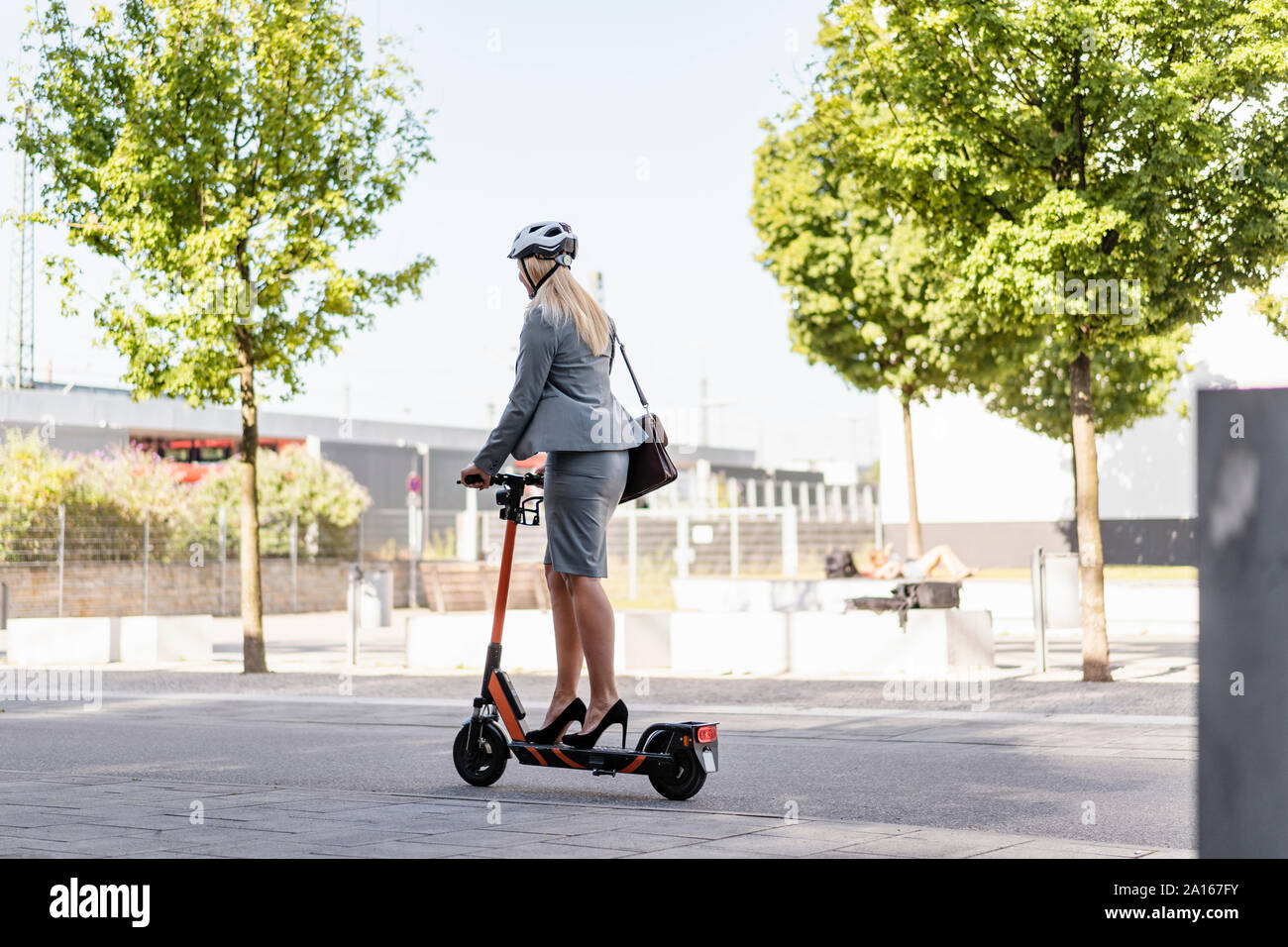 Geschäftsfrau, die das Tragen von High Heels, Elektrische Roller auf der Straße Stockfoto