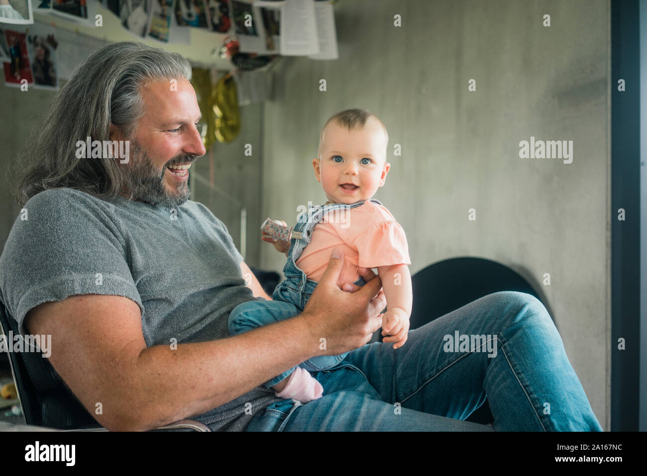 Gerne reifer Mann Holding Baby Mädchen zu Hause Stockfoto