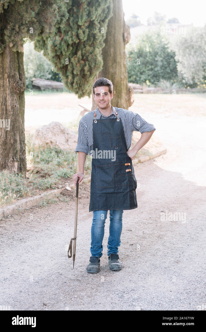 Portrait von selbstbewussten jungen Erzeuger, ein Tool auf einem Feldweg Stockfoto