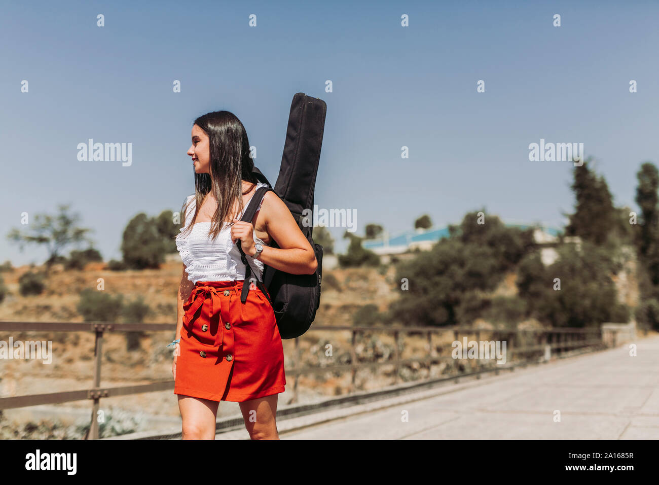 Junge Frau mit Gitarre, Wandern auf der Brücke Stockfoto