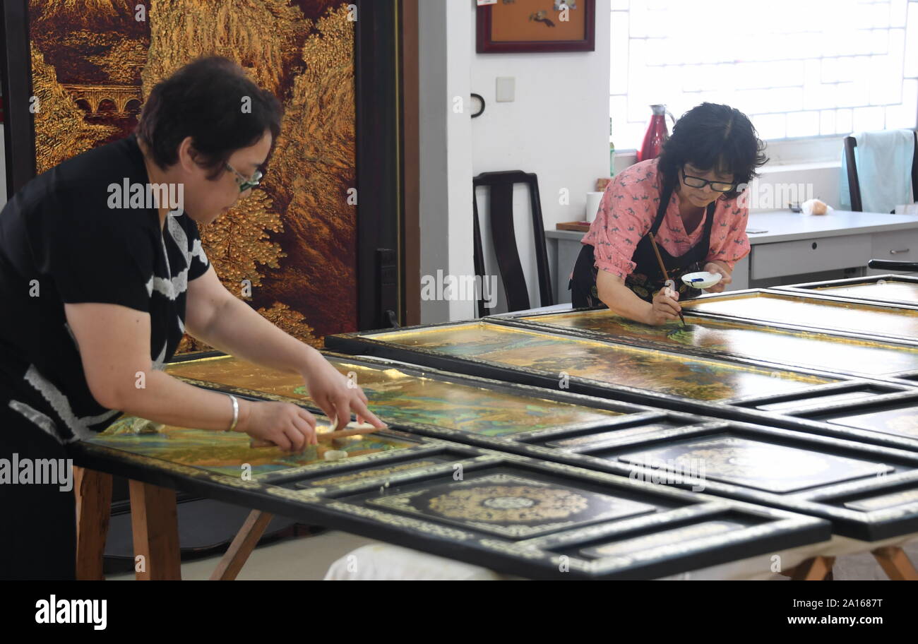 (190924)-BEIJING, Sept. 24, 2019 (Xinhua) - Hu Xin (R) und ihr Kollege Arbeiten an Bildschirmen in Peking gold Lack Gold Lack eingelegten Co., Ltd. mit Sitz in Beijing, die Hauptstadt Chinas, Sept. 19, 2019. Gold Einlegearbeiten aus Lack, ein integraler Bestandteil der lackiert und Einlegearbeiten aus Lack, ist unter den acht Peking Stil Kunsthandwerk. Gold mit Intarsien Lackarbeiten verbindet die komplexen Fähigkeiten der Carving-, Abfüll-, Whetting, Einlegearbeit und Malerei. Es verfügt über eine gold lackierte Oberfläche mit verschiedenen Edelsteinen und anderen exotischen Materialien. Hu Xin, eine 62-jährige Senior Kunst und Handwerk Meister von Peking, widmet, desi Stockfoto