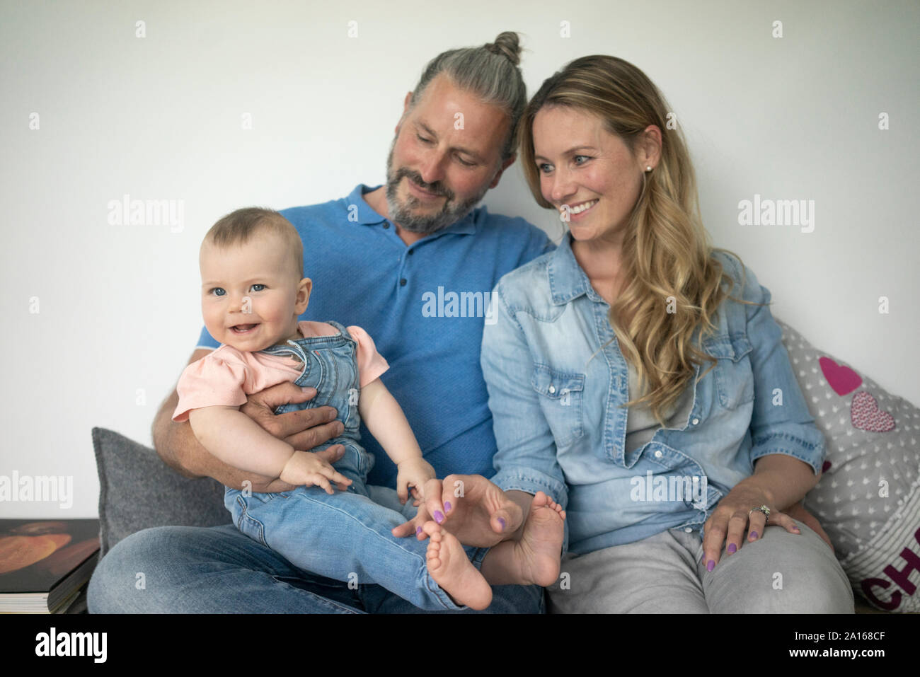 Glückliche Familie von drei auf einer Bank sitzen zu Hause Stockfoto