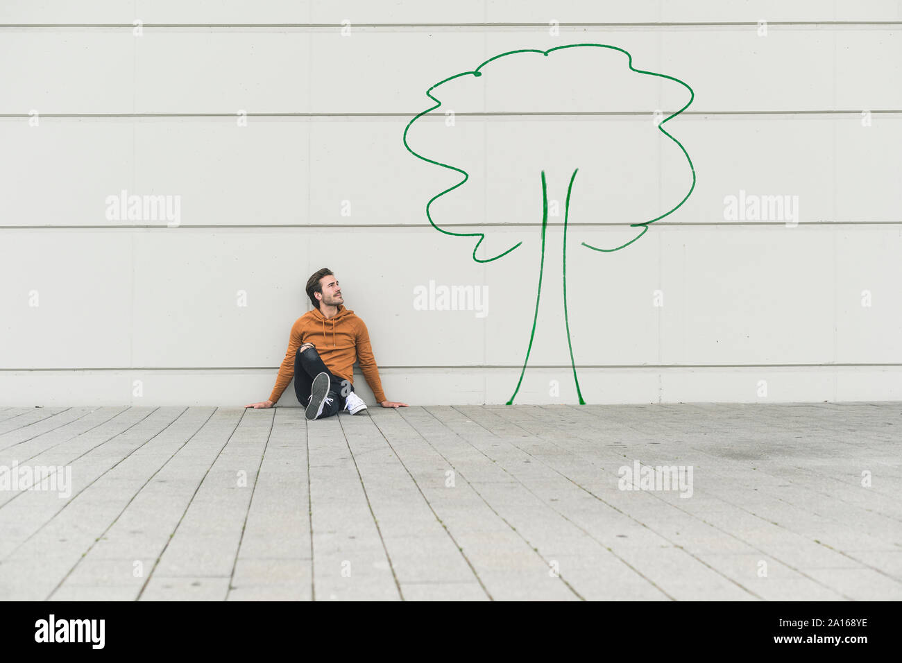 Digital composite junger Mann, der an einer Wand Stockfoto