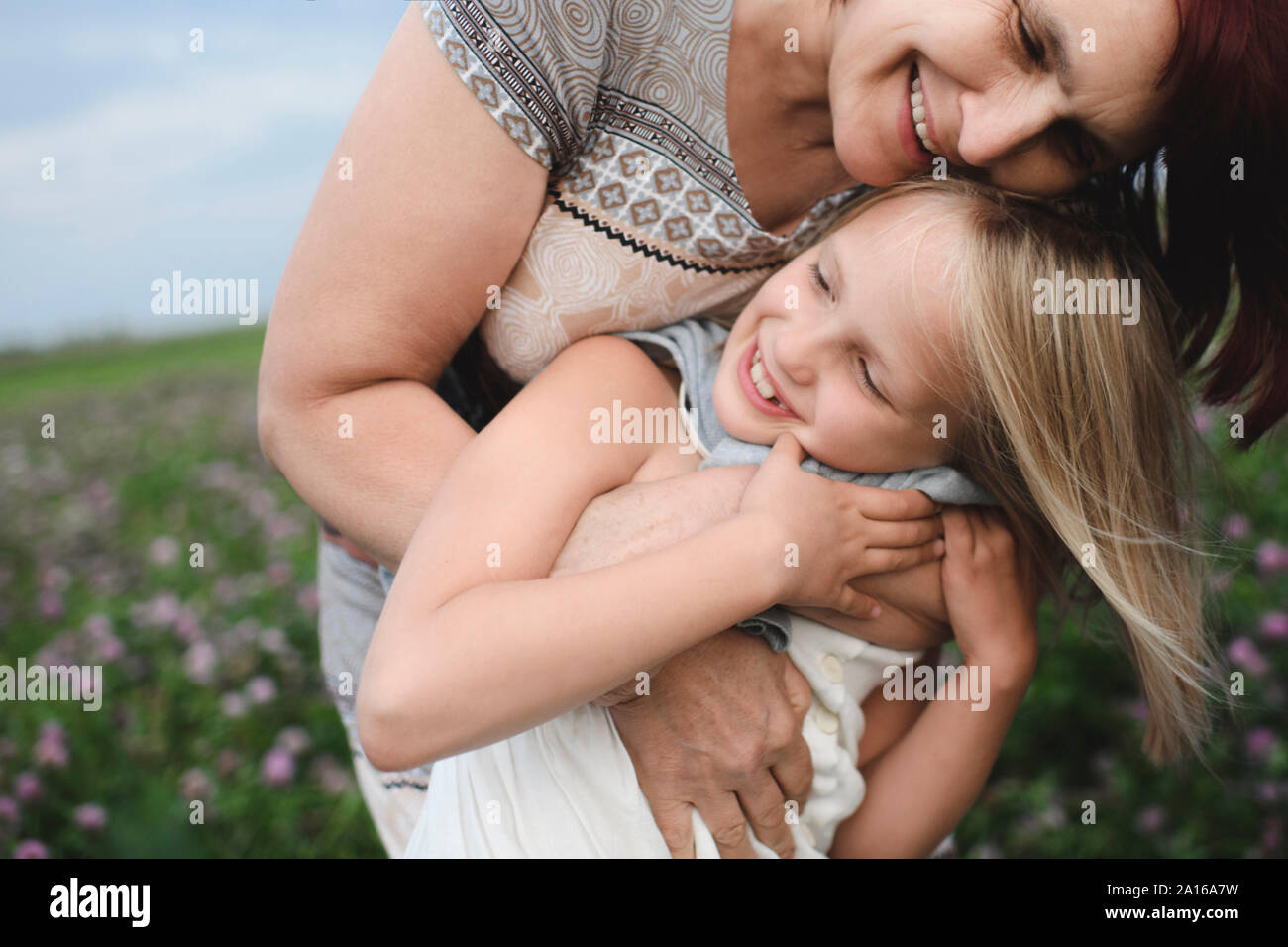 Gerne Großmutter umarmt Enkelin auf der Blumenwiese Stockfoto