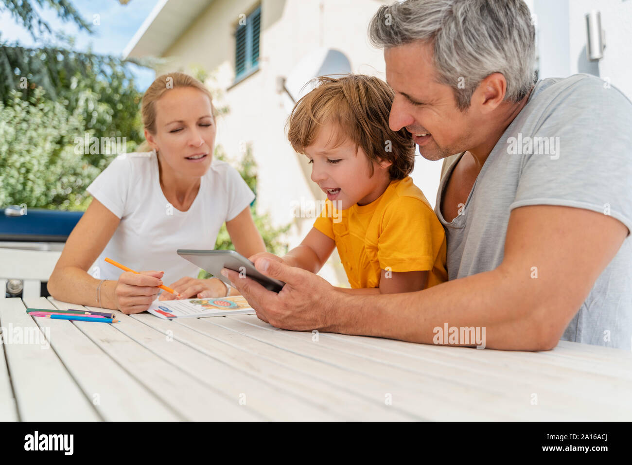 Vater, Mutter und Sohn mit Hausaufgaben und die Verwendung von Tablet zusammen auf der Terrasse Stockfoto