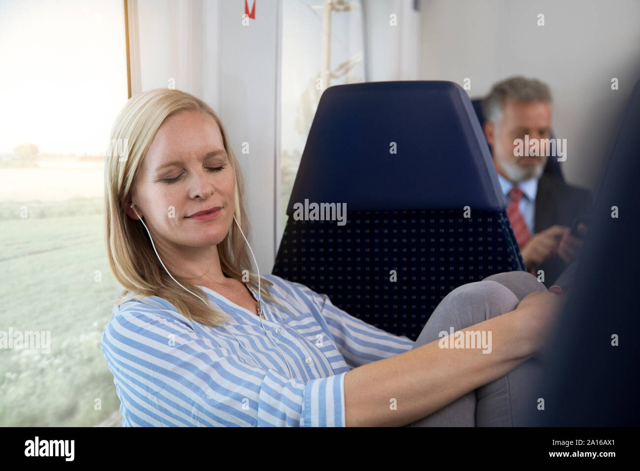 Frau im Zug sitzen, Musik hören mit Kopfhörern Stockfoto