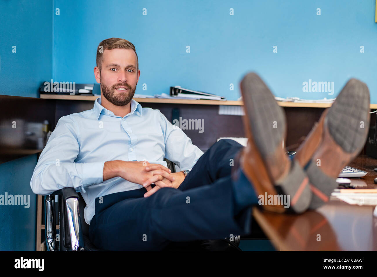 Porträts der Geschäftsmann mit Füßen auf dem Schreibtisch im Büro Stockfoto