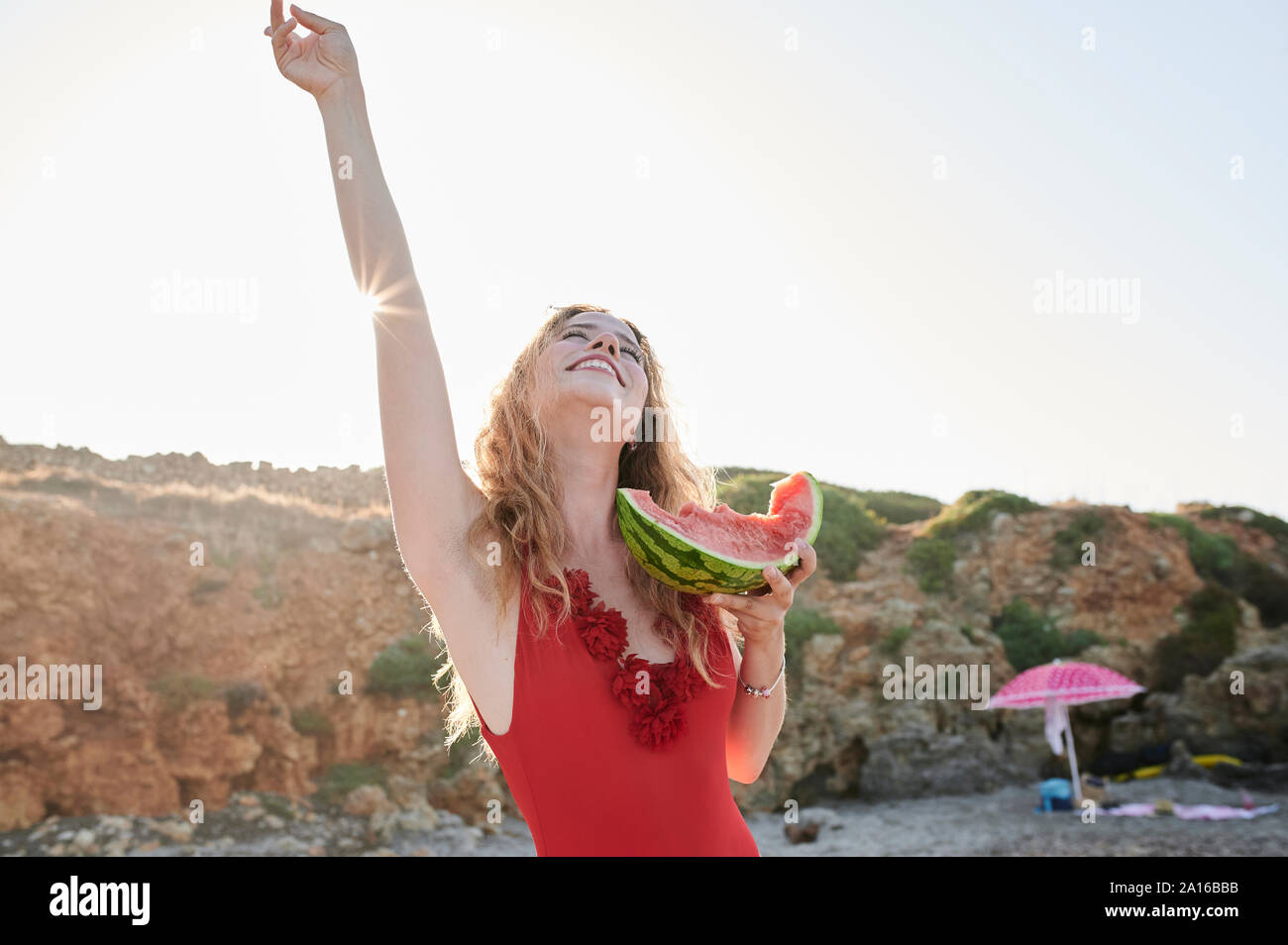 Unbeschwerte junge Frau mit Wassermelone Schicht am Strand Stockfoto