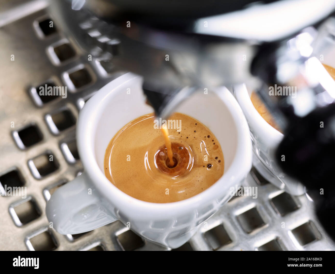 Espresso fließt in eine Tasse Espresso Stockfoto