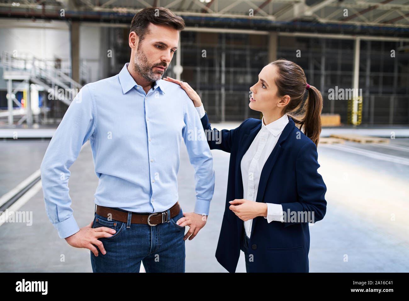 Geschäftsfrau im Gespräch mit enttäuscht Geschäftsmann in einer Fabrik Stockfoto