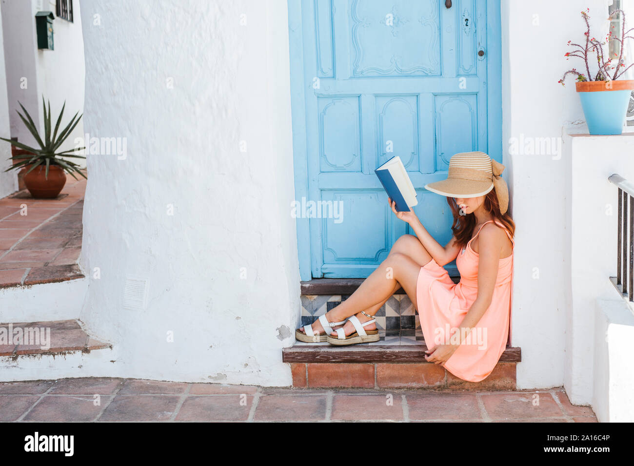 Junge Frau mit Buch auf Schritt des Hauses Eingang, Nerja, Malaga, Spanien Stockfoto