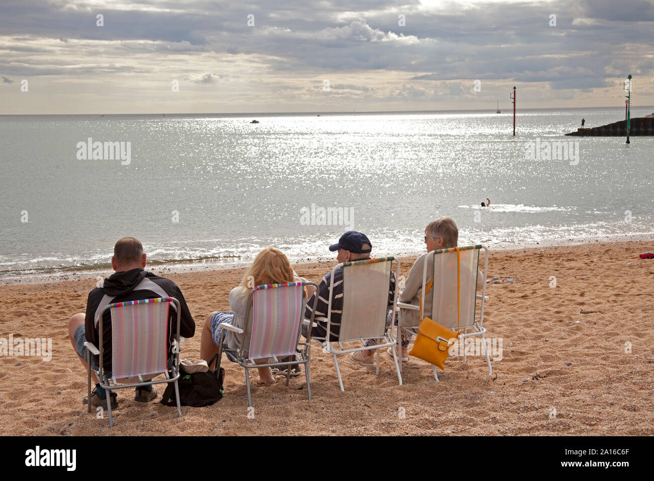 West Bay, sitzen auf Stühlen, East Cliff Beach, Bridport, Dorset, England, Großbritannien Stockfoto