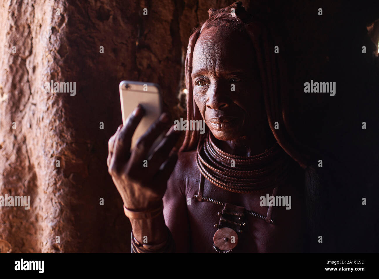 Alte Frau Himba ihr Smartphone prüfen, Oncocua, Angola Stockfoto