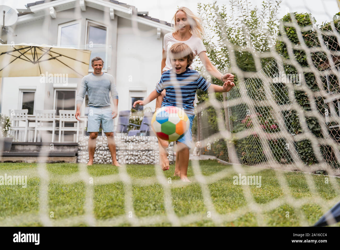 Glückliche Familie Fußball spielen im Garten Stockfoto