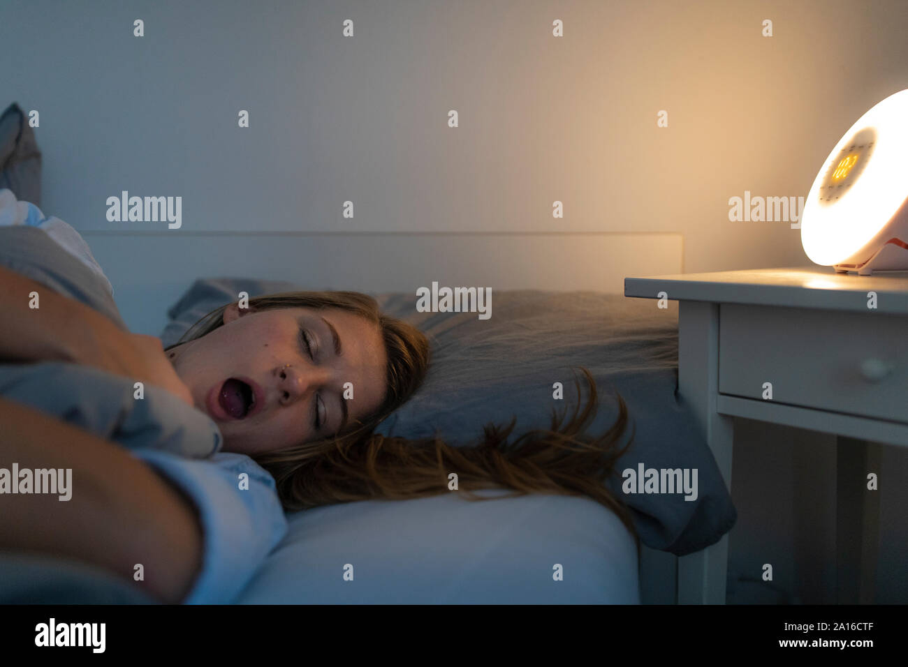 Junge Frau im Bett zu Hause liegen in der Nacht gähnen Stockfoto