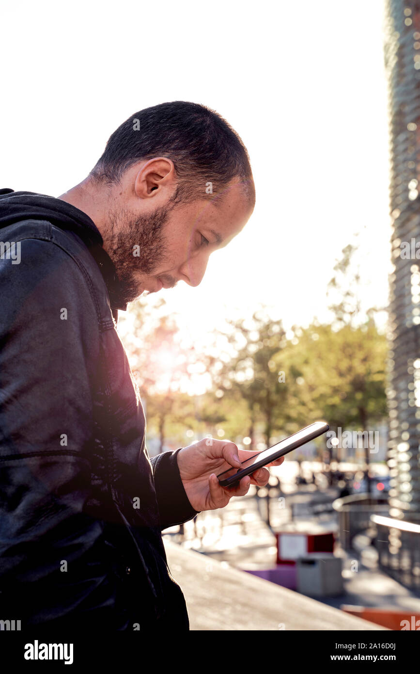 Mann mit Handy bei Sonnenuntergang in der Stadt, Barcelona, Spanien Stockfoto