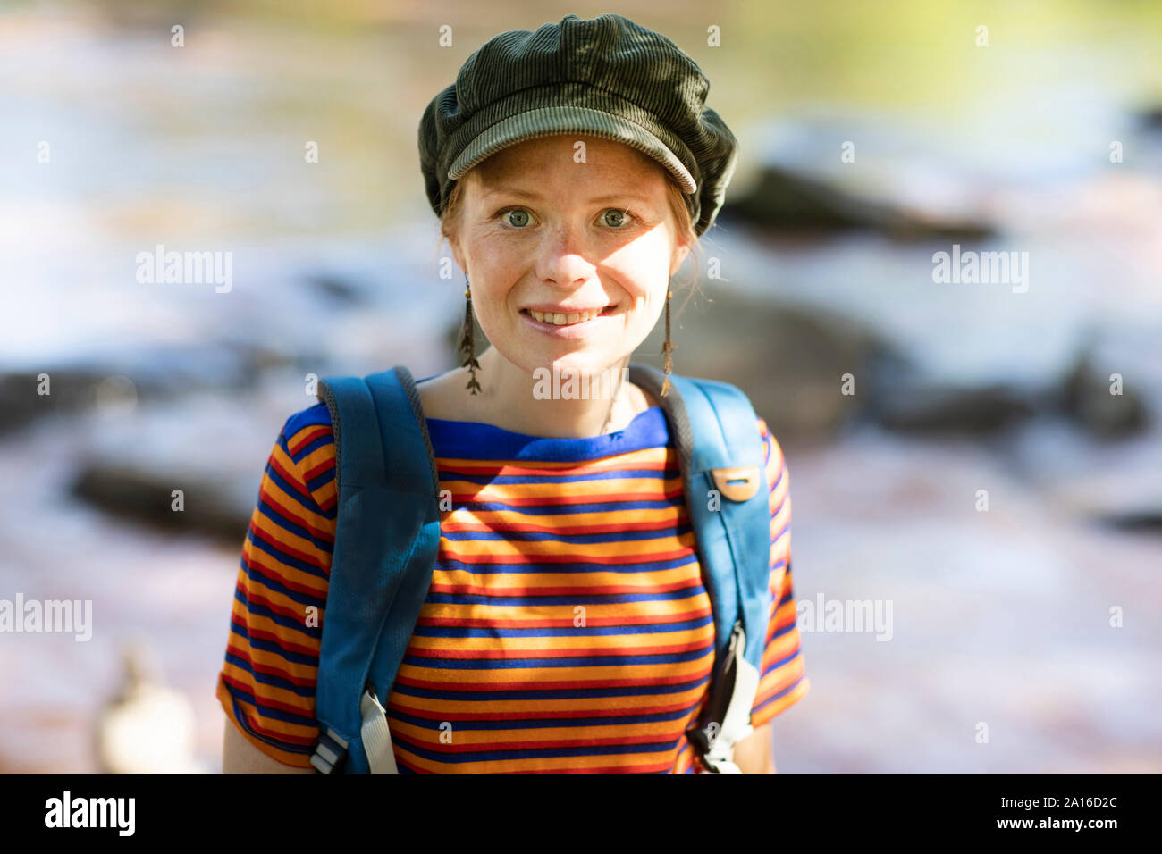 Porträt einer lächelnde Frau mit Rucksack an einem Flußufer Stockfoto