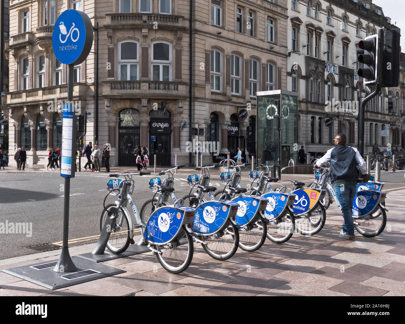 Dh Fahrradverleih Fahrräder TRANSPORT Mann mit Zahlen wie sie Fahrrad Regelung Cardiff Wales Bike für die Einstellung de gehen Stockfoto