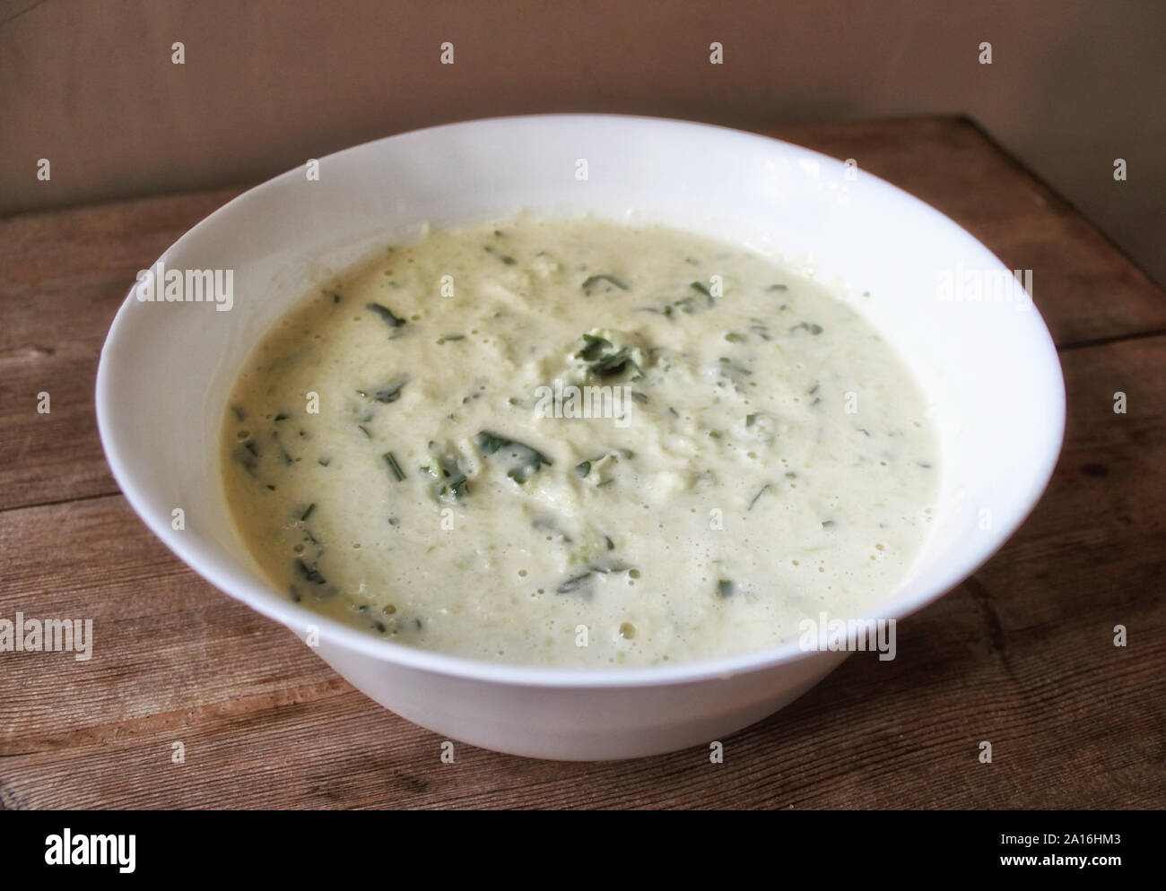 Teig für Gemüse Zucchini Pfannkuchen mit Kräutern, die in weiße Schüssel. Selektive Weichzeichner. Text kopieren. Sommer Herbst Gemüse ernten Konzept Stockfoto