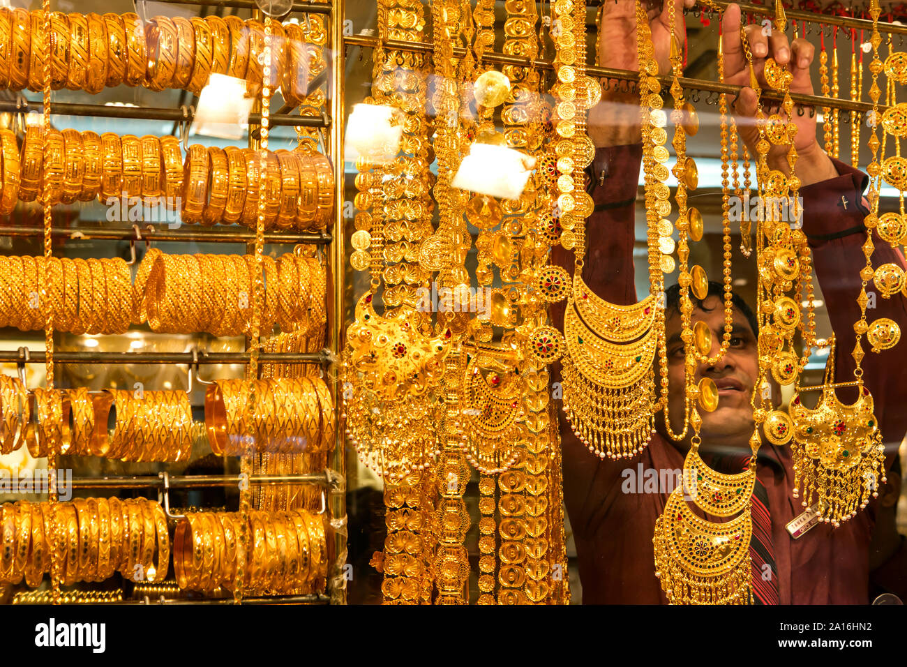 DUBAI - ein ladenbesitzer nimmt eine goldene Halskette aus seinem Fenster Anzeige im Gold Souk. Stockfoto