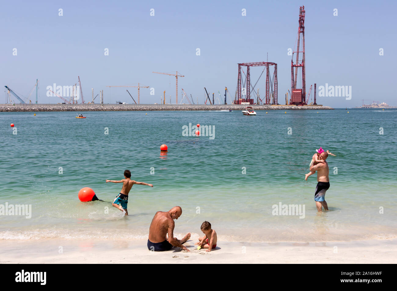 DUBAI - Touristen am Strand von Dubai Marina. Im Hintergrund die Baustelle des größten Riesenrad der Welt. Stockfoto