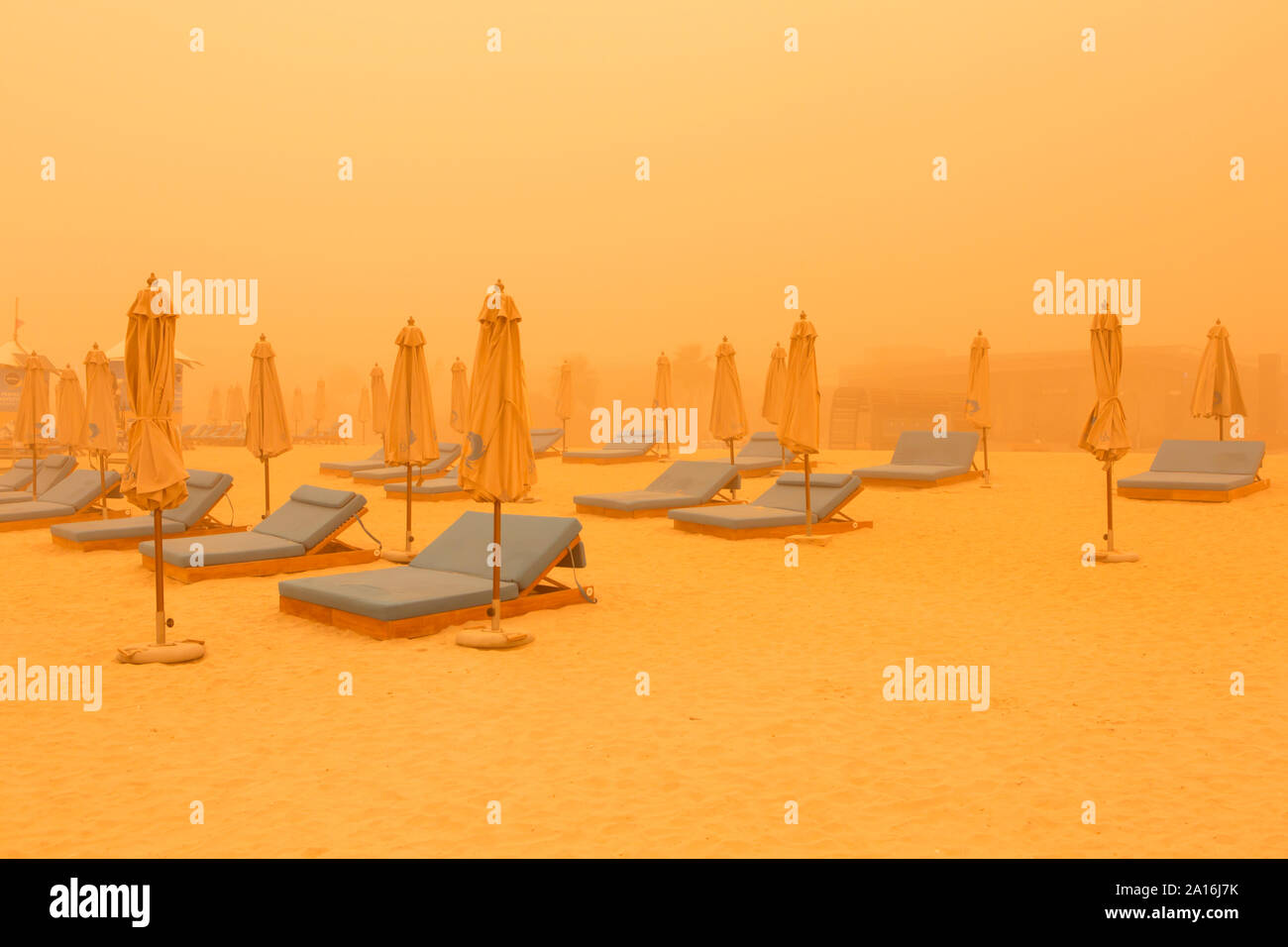 DUBAI - Leere Liegestühle und Sonnenschirme am Strand in Dubai Marina durch den Dunst der massiven Sandsturm, dass die Emirate am Donnerstag schlagen gesehen. Stockfoto