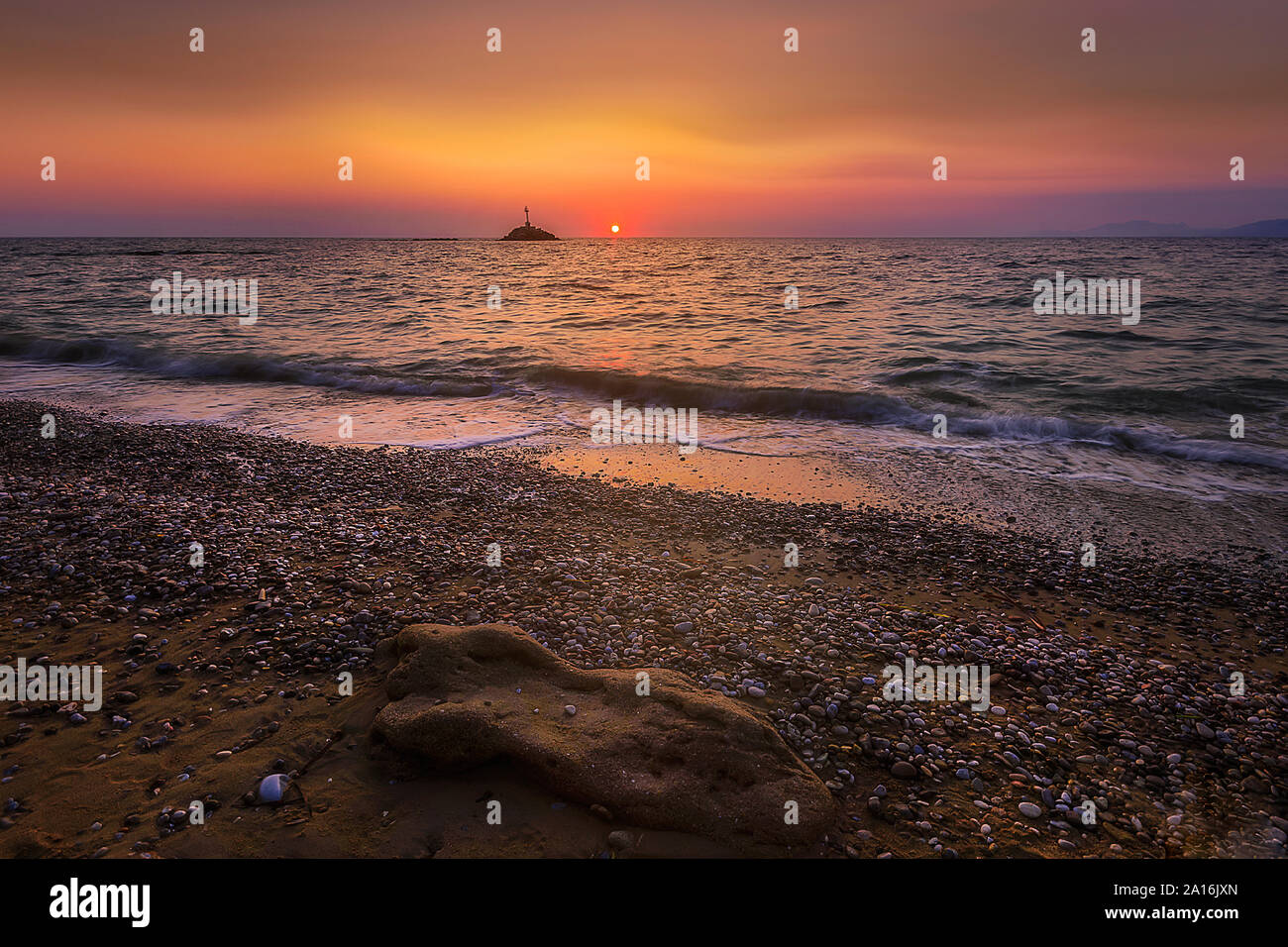 Einen schönen Sonnenuntergang am Strand genießen dieser verzauberten Licht. Auf dem Hintergrund gibt es einen kleinen Leuchtturm Stockfoto