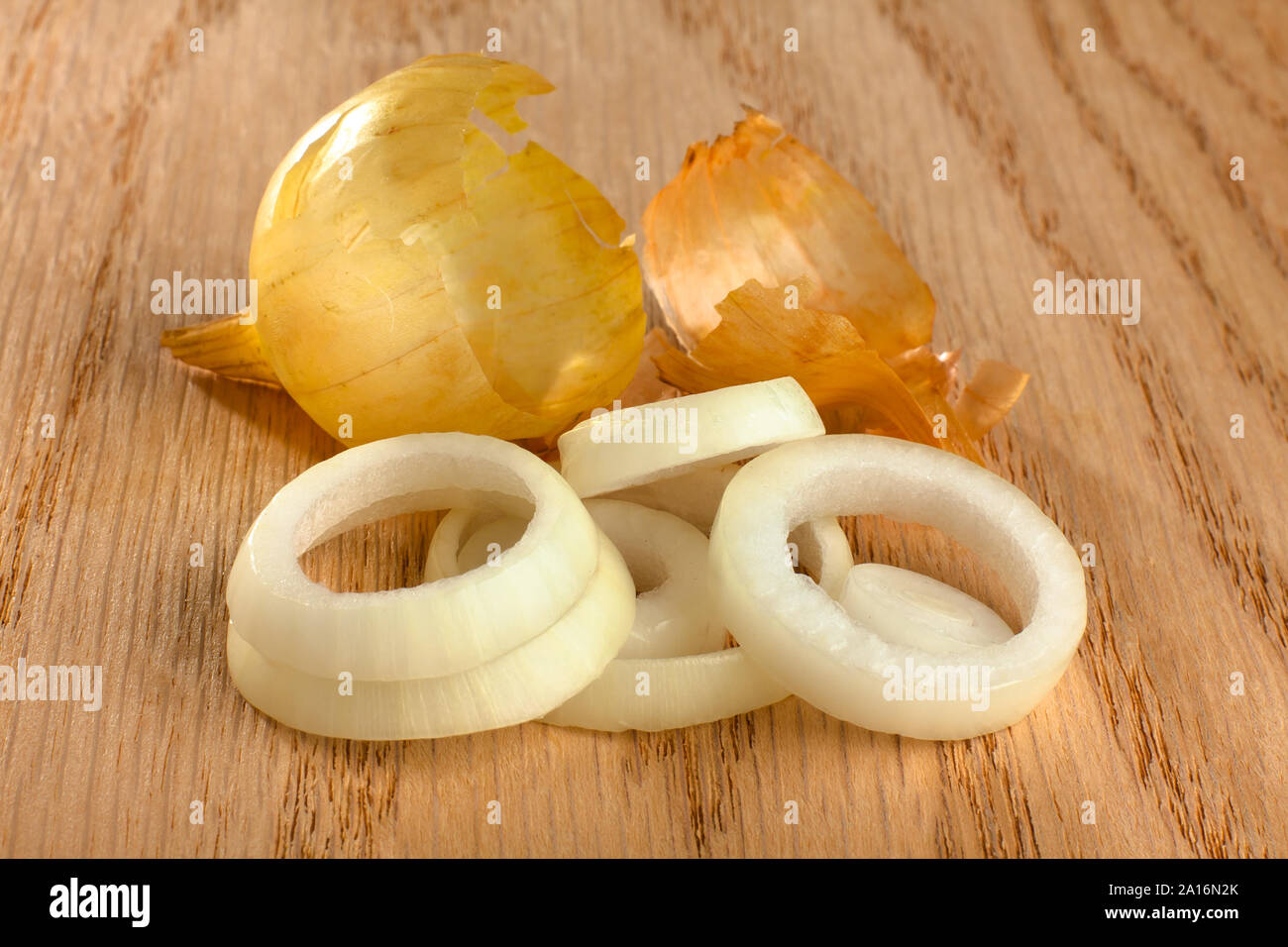 Ringe von Zwiebel mit Schale auf hölzernen Hintergrund, Nahaufnahme Stockfoto