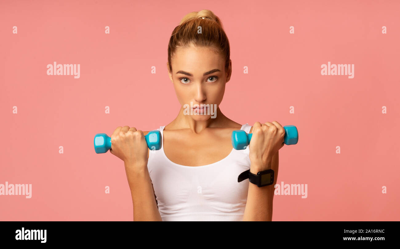Motivierte Frau Training mit Kurzhanteln auf rosa Hintergrund, Panorama Stockfoto