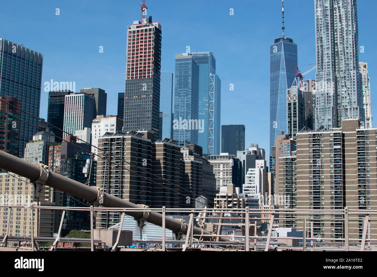 Blick auf die Skyline von Lower Manhattan mit der Stahlkonstruktion der Brooklyn Brücke im Vordergrund. Das One World Trade Center und Gehry Berndorf sieht Stockfoto