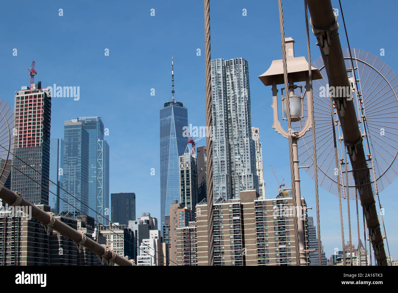 Blick auf die Skyline von Lower Manhattan mit der Stahlkonstruktion der Brooklyn Brücke im Vordergrund. Das One World Trade Center und Gehry Berndorf sieht Stockfoto