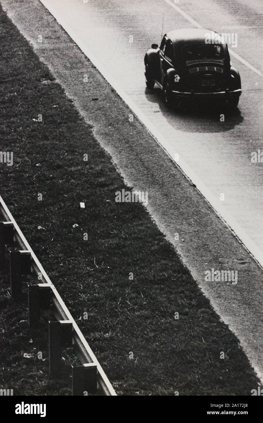 Feine schwarze und weiße Kunst Fotografie von den 1970er Jahren von Volkswagen Beetle Auto entlang einer Schnellstraße fahren. Stockfoto