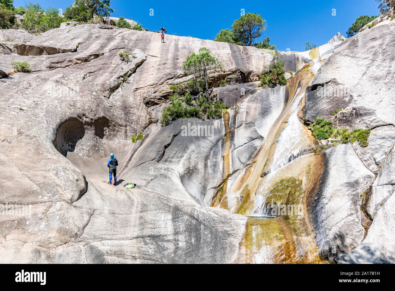 Menschen canyoning neben einem Wasserfall in der berühmten Purcaraccia Canyon in Bavella im Sommer, Korsika, Frankreich Stockfoto
