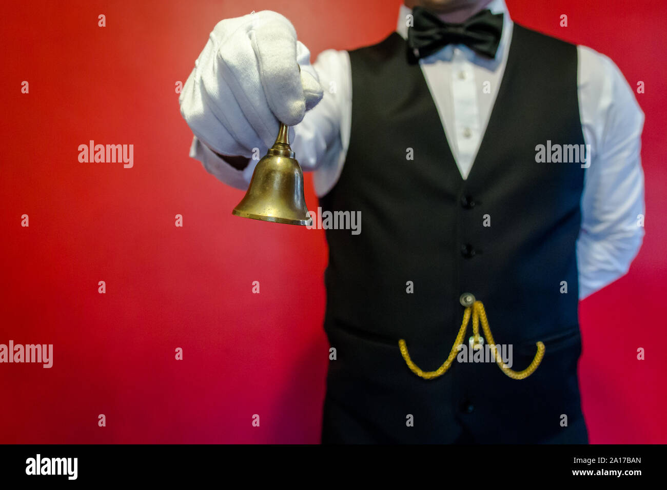 Butler Klingelt Messingglocke. Konzept der Dienstleistungsbranche und professionelle Gastfreundschaft und Höflichkeit. Stockfoto