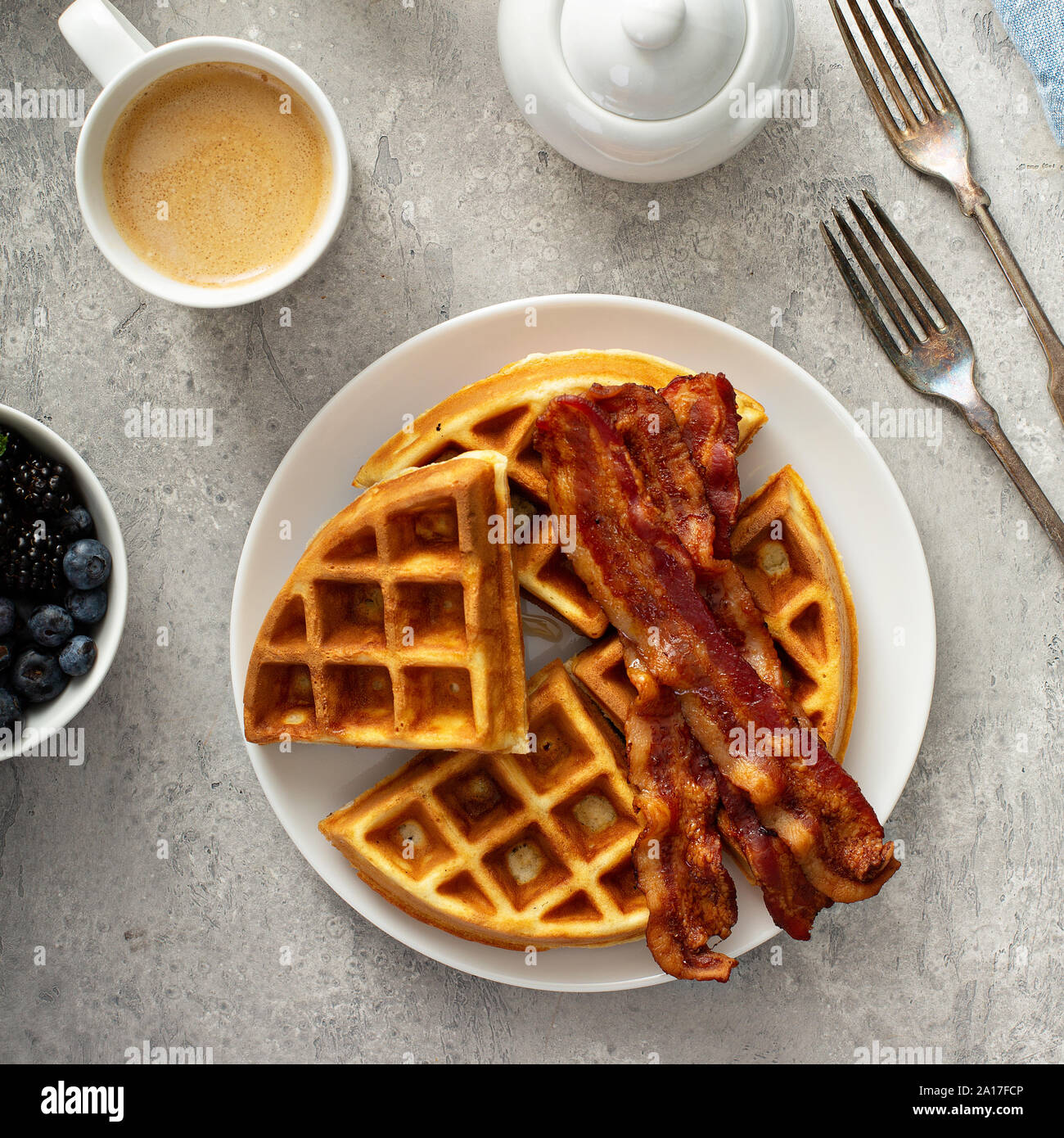 Frühstück Teller auf dem Tisch mit Waffeln und Speck, Beeren und Ahornsirup Stockfoto