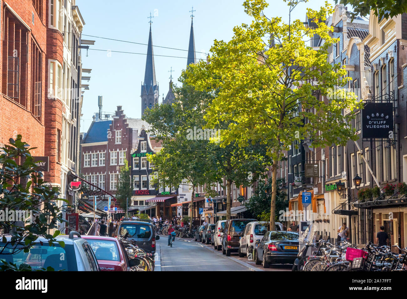 Spuitstraat mit typisch holländischen Häusern, der Verkehr, die geparkten Autos und Fahrräder an einem sonnigen Nachmittag. Amsterdam, Niederlande. Stockfoto