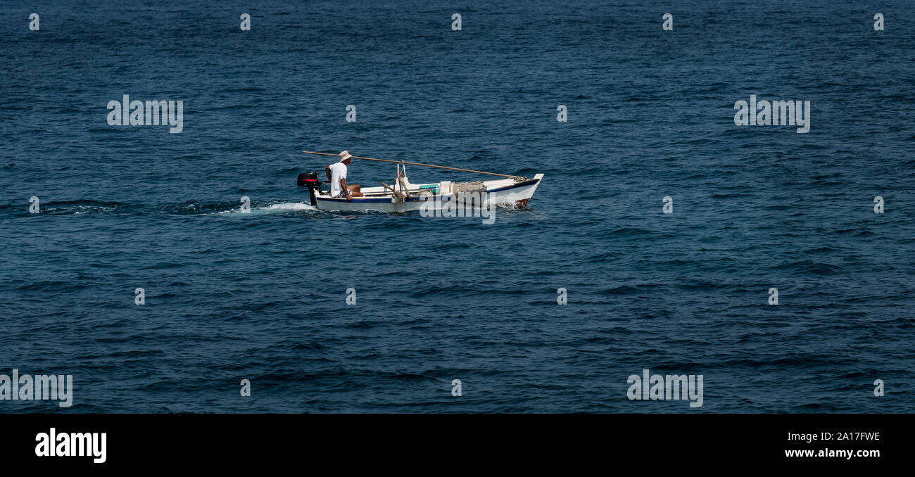 Alte hölzerne Motorboot mit einzelnen Mann am Mittelmeer Stockfoto