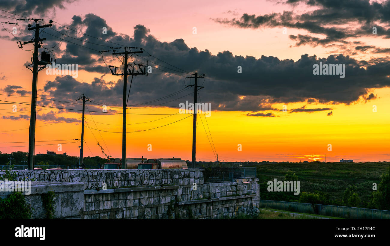 Holz- elektrischen Polen über eine Mauer aus Stein bei Sonnenuntergang Stockfoto