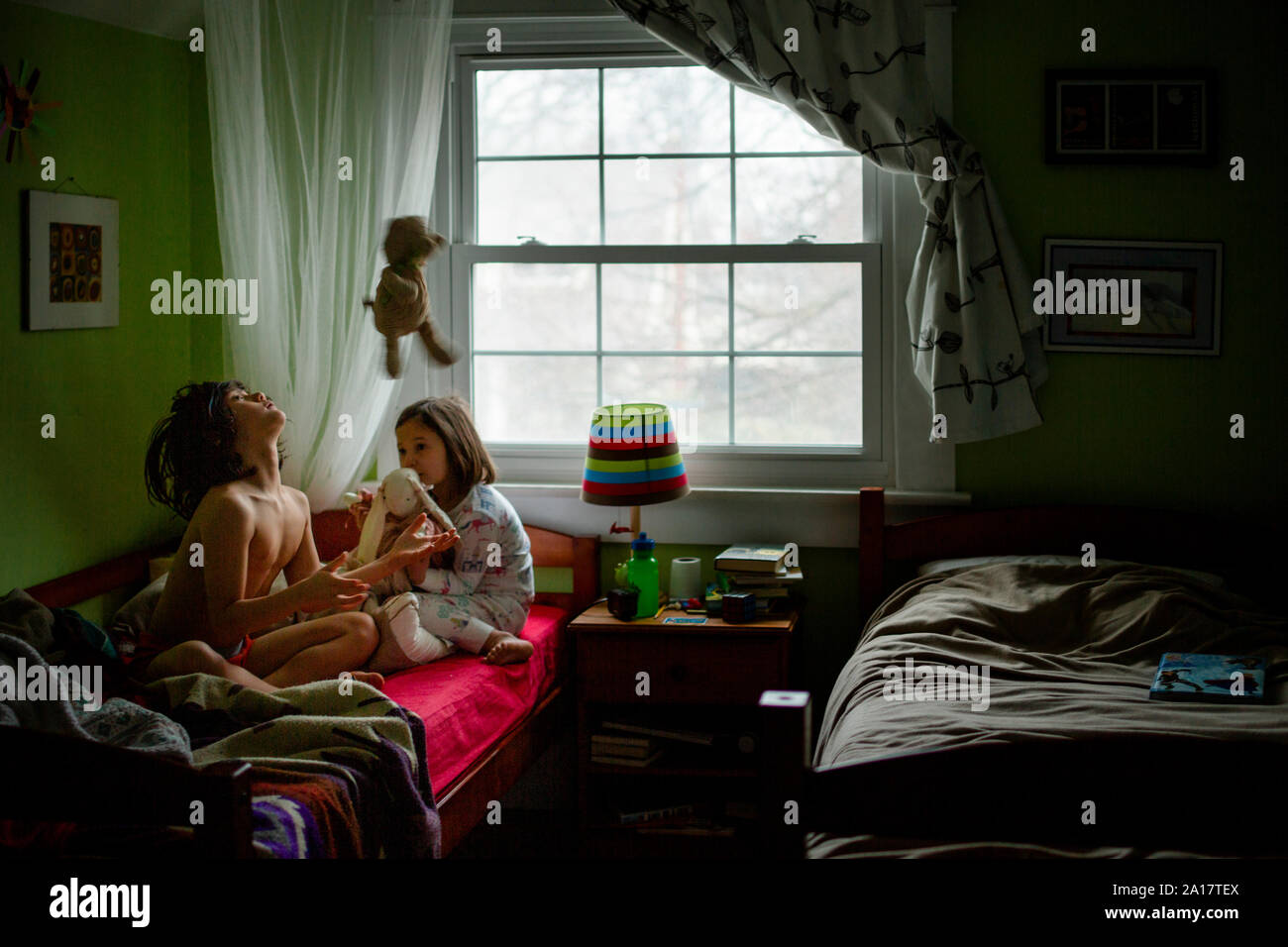 Zwei Kinder im Schlafanzug spielen, mit ausgestopften Tieren in einem Schlafzimmer Stockfoto