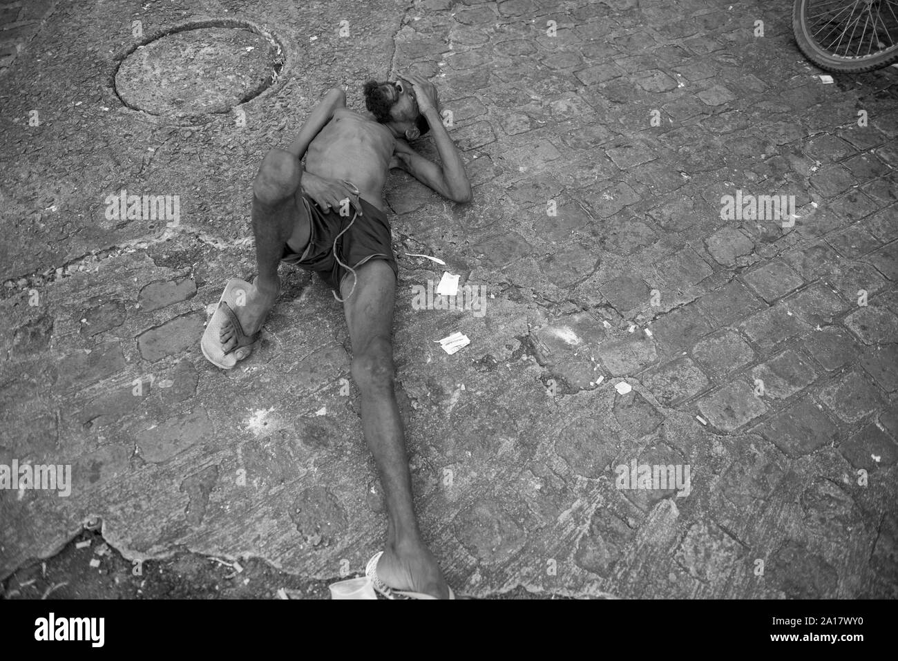 Obdachlose Menschen mit angeborenen Krankheit liegen auf gepflasterten Straße Stockfoto