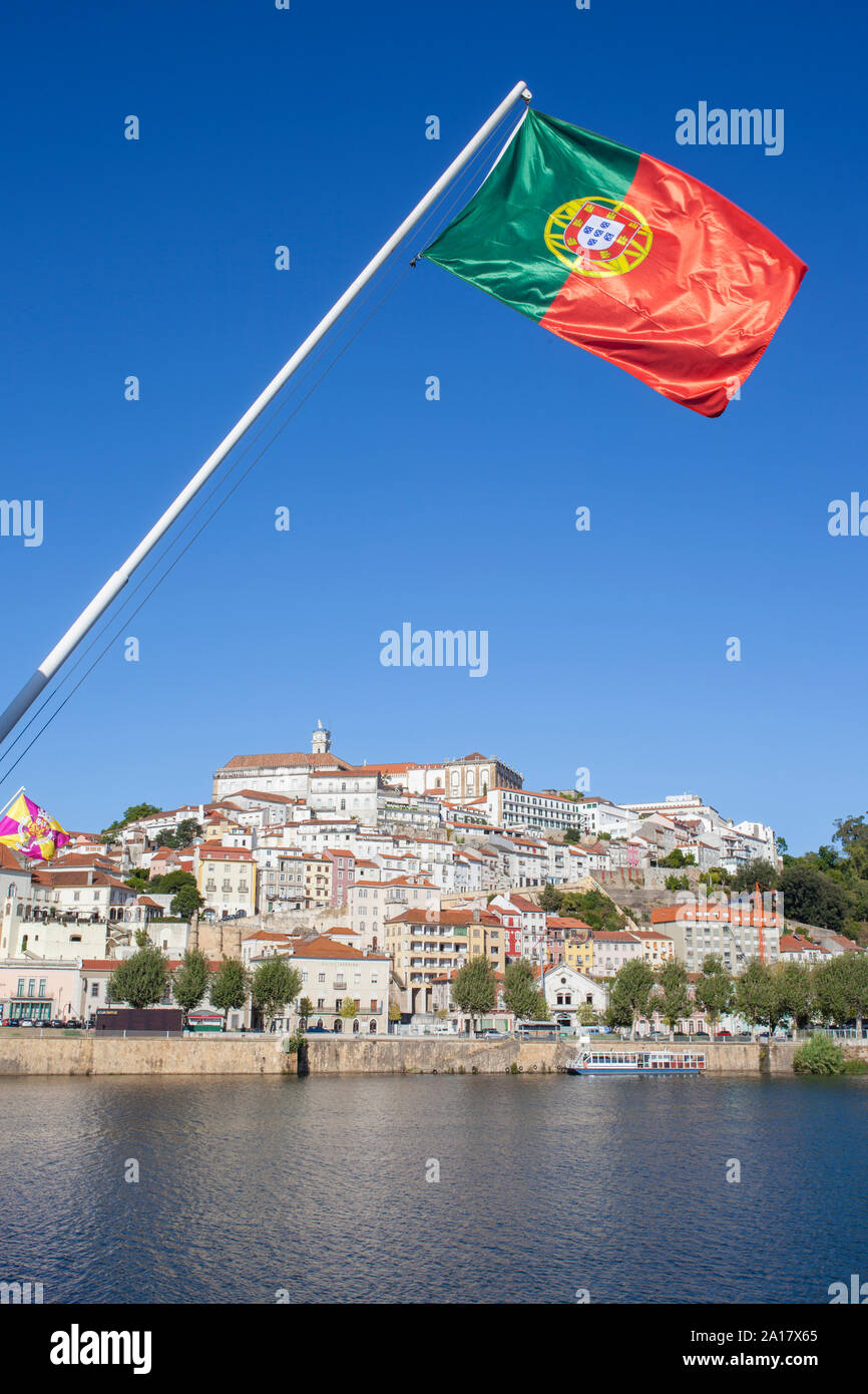 Blick auf die Altstadt von Coimbra aus Santa Clara Brücke mit Portugal Flagge das Weben in den blauen Himmel. Coimbra ist eine wunderschöne historische Stadt mit vielen touristischen sp Stockfoto