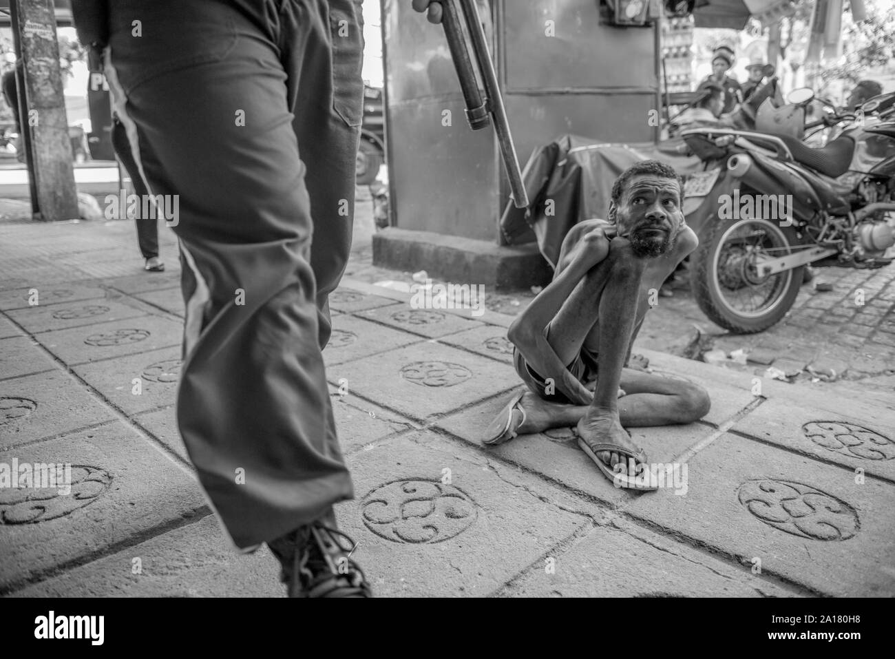 Obdachlose Menschen mit angeborenen Krankheit an Polizei Mann mit einer Pistole auf der Suche Stockfoto