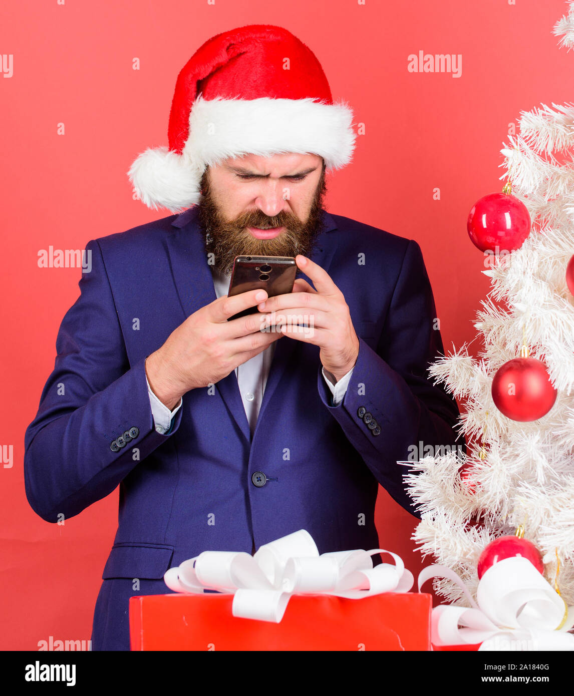 Gruß an Weihnachten mobile Nachricht senden. Kurze Weihnachten wünscht.  Manager und Kollegen gratulieren online. Lesen Sie mehr Weihnachten Gruß.  Man bärtige Hipster tragen Anzug und Santa hat halten Smartphone  Stockfotografie - Alamy