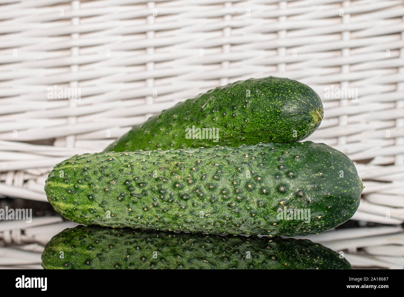 Hinter der Gruppe der zwei ganze frische Beizen Gurke mit geflochtenen Rattan Stockfoto