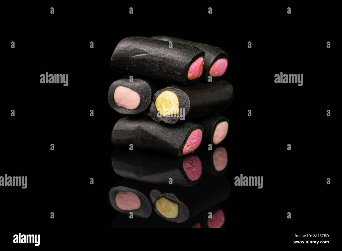 Gruppe von sechs ganze süsse schwarz Lakritz Bonbons auf schwarzem Glas isoliert Stockfoto
