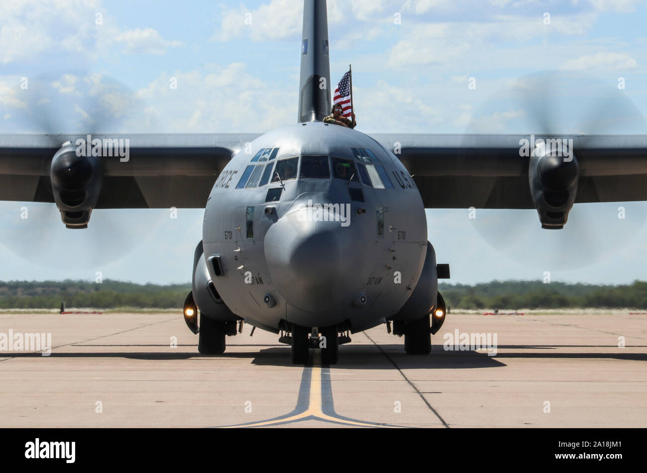 Einen Flieger von Dyess Air Force Base, Texas, eine US-Flagge als Flieger Rückkehr von einer Bereitstellung in Dschibuti, Afrika, Sept. 19, 2019. Dyess Flieger zur Bekämpfung der Lieferfähigkeit durch taktische Luftbrücke und airdrop Operationen sowie humanitäre Bemühungen und aeromedical Evakuierungen in den USA Afrika Befehlsbereich der Verantwortung während der Bereitstellung. (U.S. Air Force Foto: Staff Sgt. David Owsianka) Stockfoto