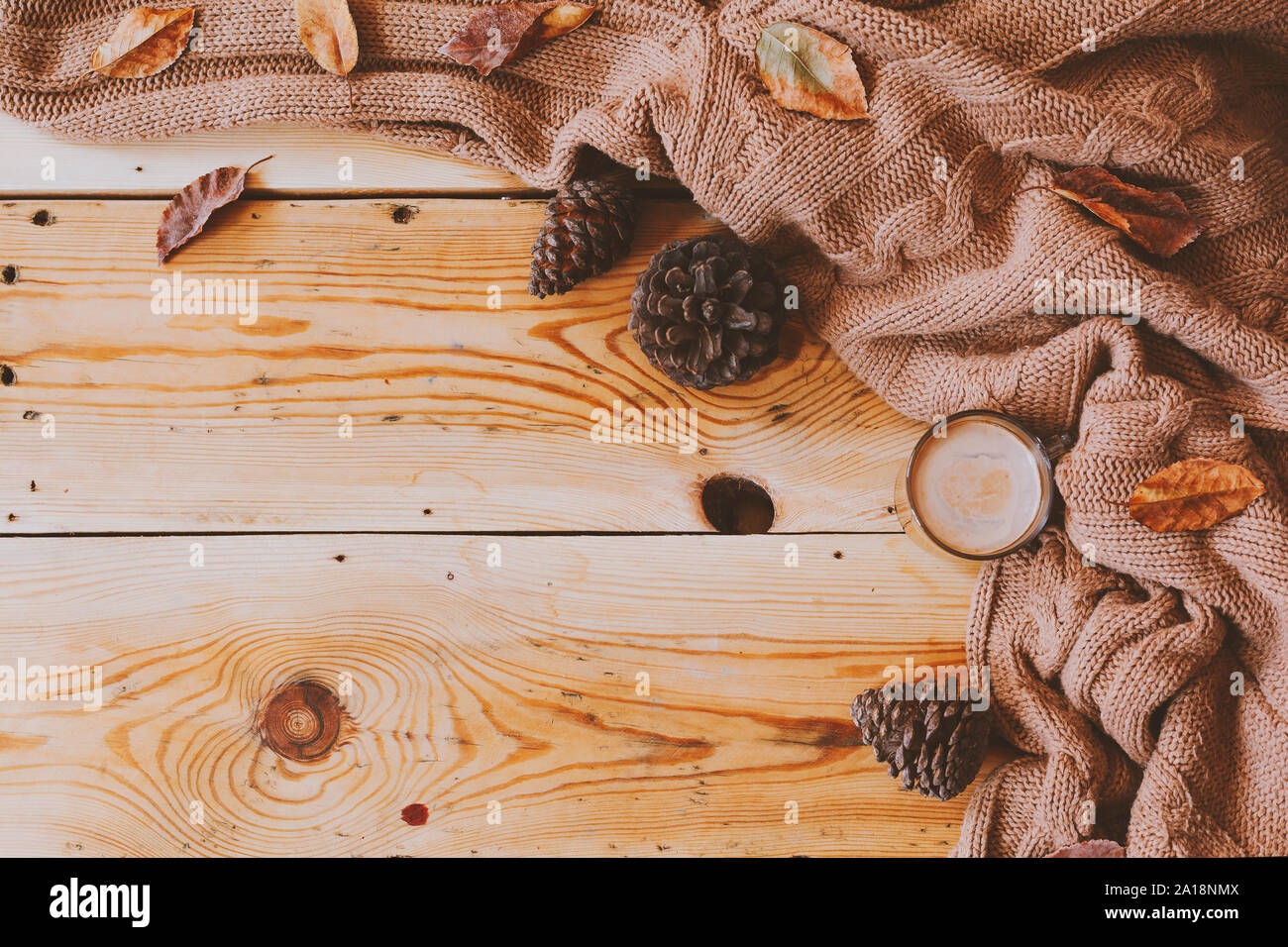Herbst Hintergrund. Eine Tasse heißen Kaffee, strickschal, und kiefernzapfen auf einem Holztisch. Herbst Kaffee. Gestrickten Wollpullover, Kaffee und Herbstlaub Stockfoto