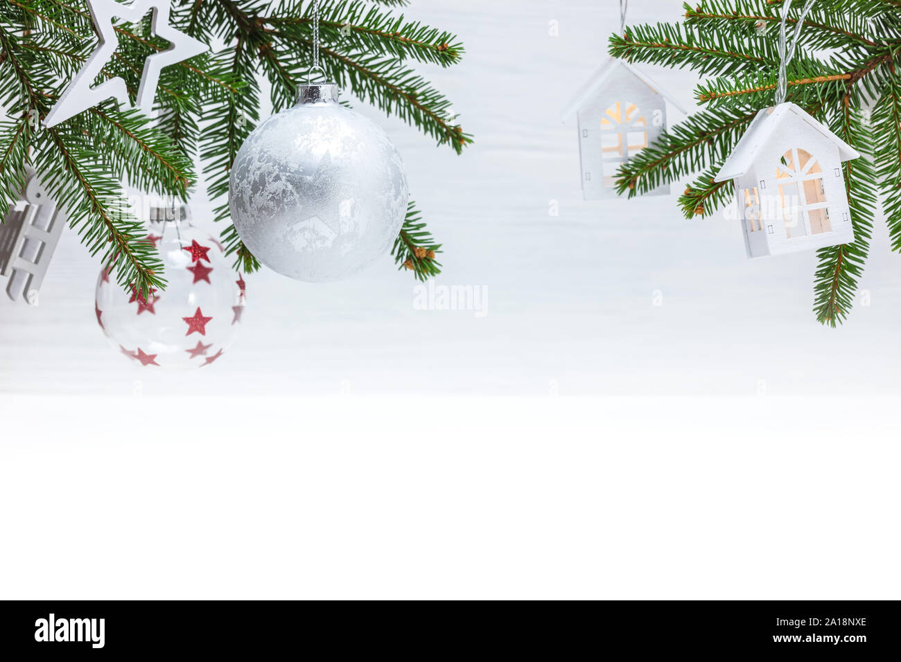 Verschiedene Kugeln aus Glas und Holz- Weihnachtsschmuck hängen an grünen Tannenbaum Äste gegen weiße Wand Hintergrund Stockfoto
